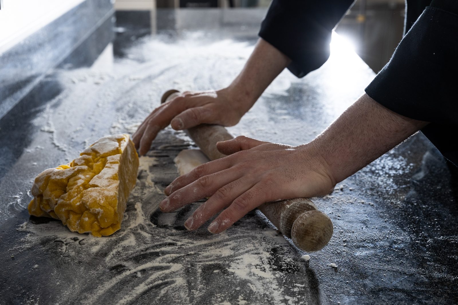 Hands rolling fresh pasta dough